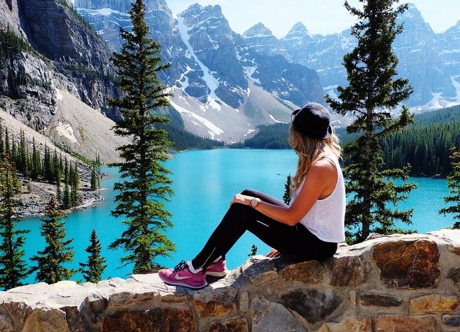 A woman pursues a lifetime of adventures as she sits on a rock overlooking a lake in Banff National Park.