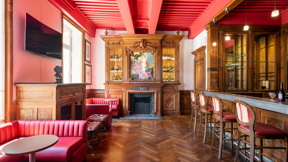 A bar with red leather chairs and a fireplace.