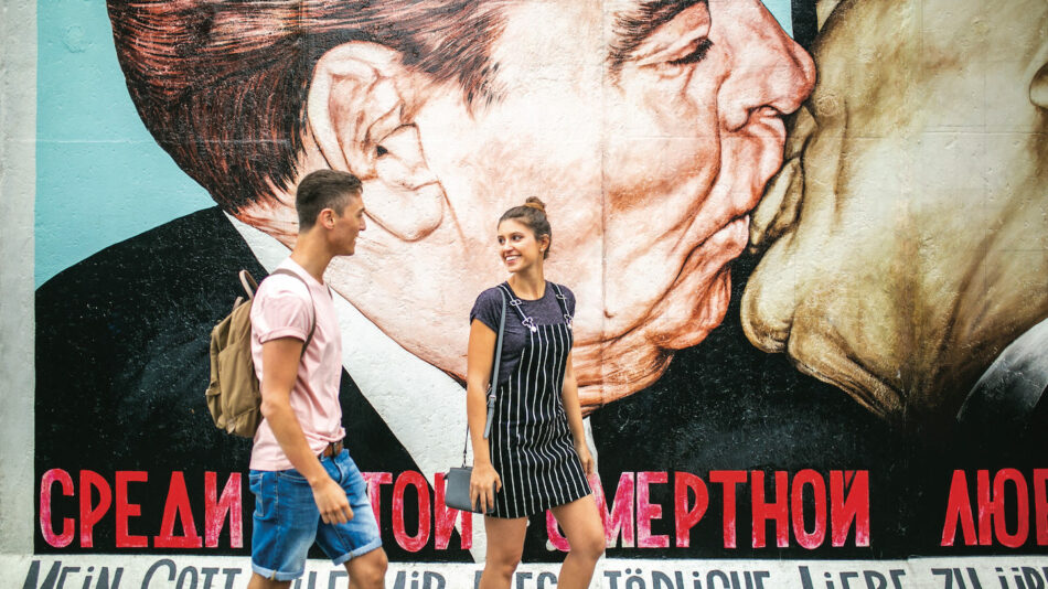 Two people in Berlin in front of political graffiti