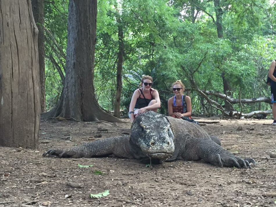 Two women posing next to a komodo lizard, seeking the cure for a break-up.