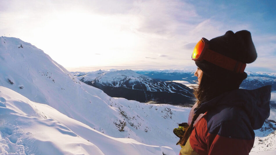 A person is standing on top of a mountain, feeding their travel addiction.