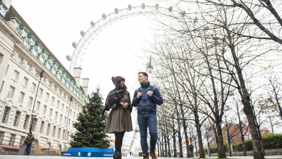 Couple strolling in front of the London Eye.