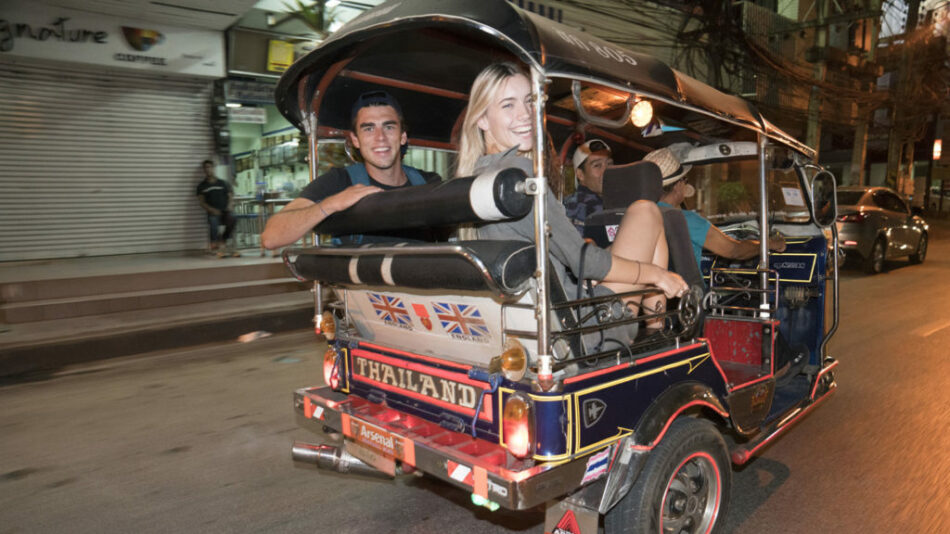 A group of people riding in a tuk-tuk in Southeast Asia at night.