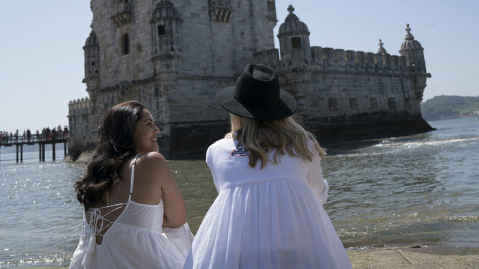 Two women in white dresses radiating self love standing in front of a castle.