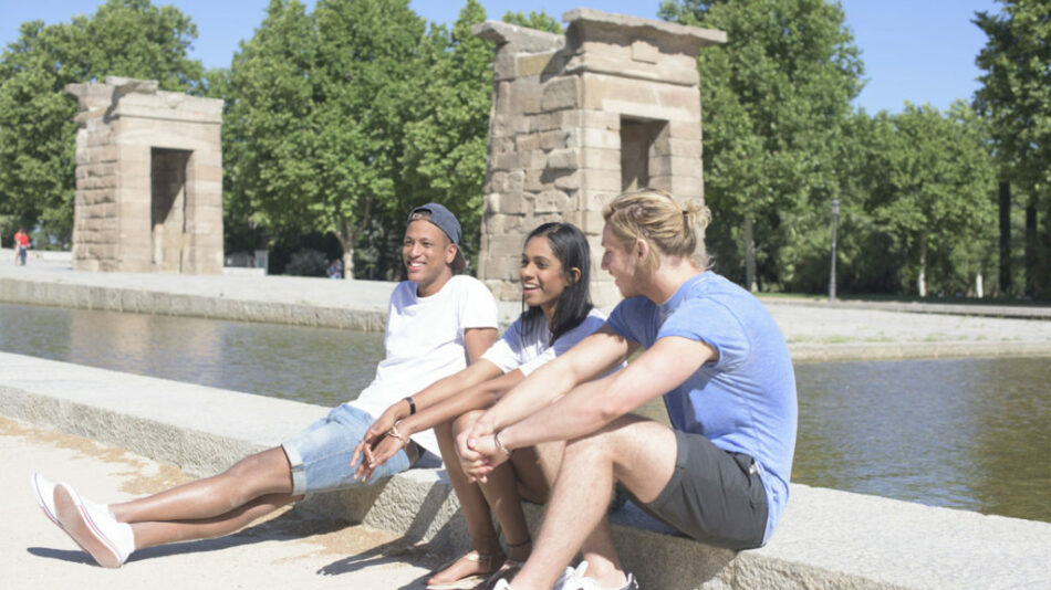 A group of people practicing self love by sitting on the edge of a peaceful pond.