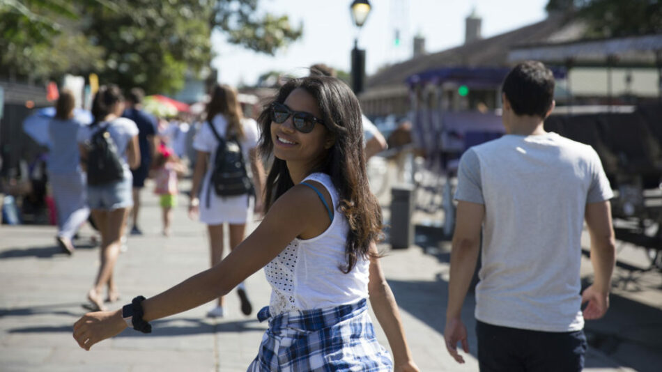 A Contiki social media manager is walking down the street with a frisbee.