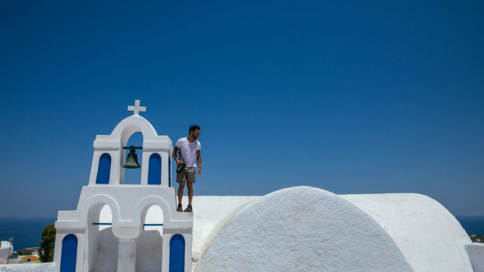 A man practicing self love on top of a white church.