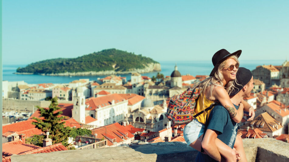 A couple on a Contiki trip hugging on top of a hill overlooking the city in Croatia.