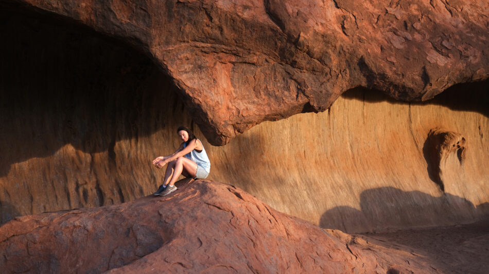 A woman sitting inside a rock cave.