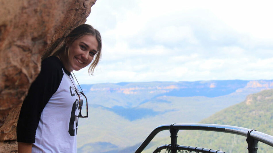 A woman on a Contiki trip in Australia, leaning against a cliff in the Blue Mountains.