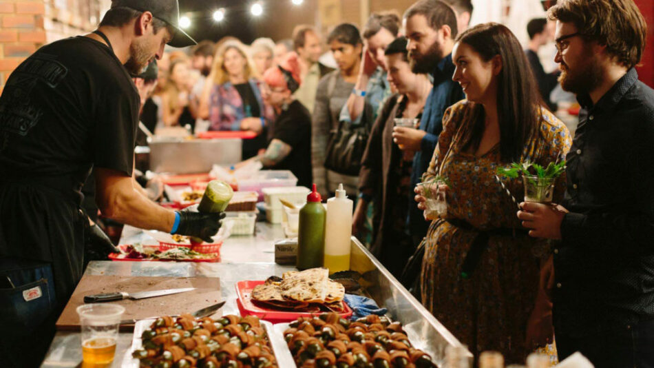 A group of people gathered around a table filled with food at a big feastival.