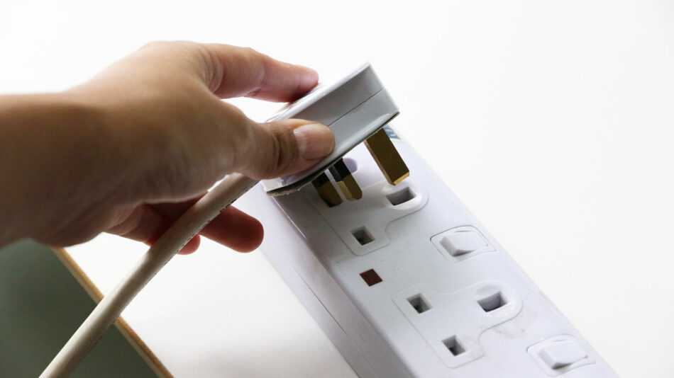 A person putting a plug into a socket.