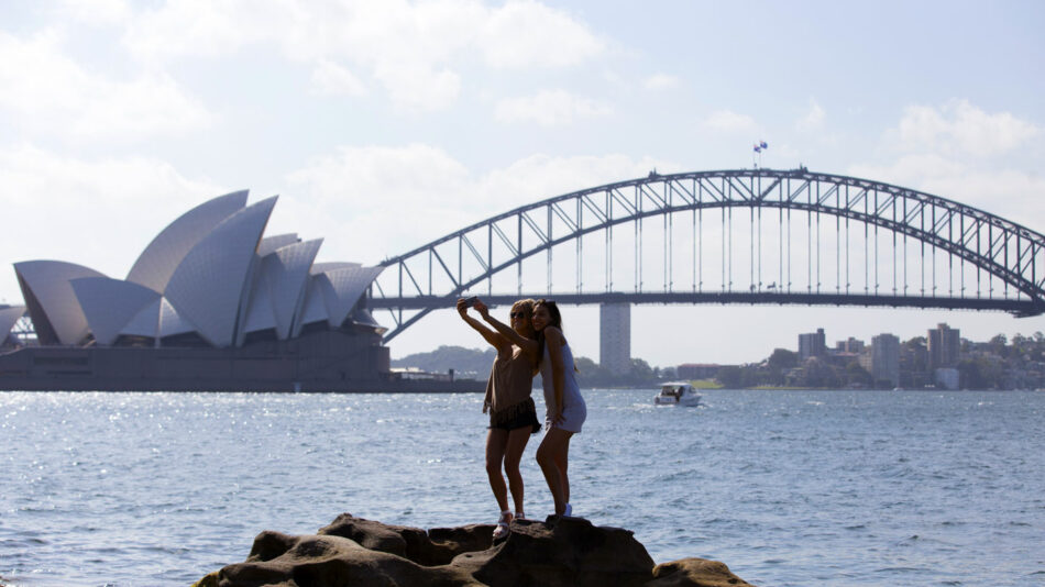 Two women standing on rocks in front of the Sydney Opera House, one of the top destinations of 2017.