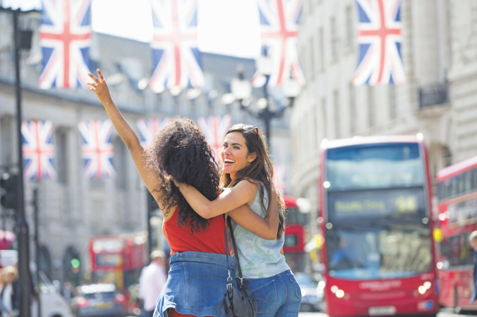 Two young women in london waving at british flags.