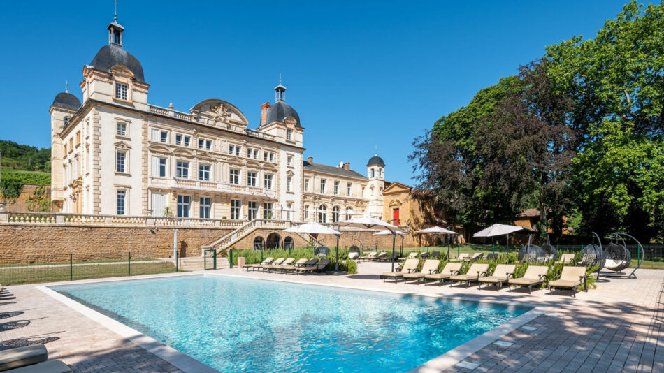 A swimming pool in front of a large castle.