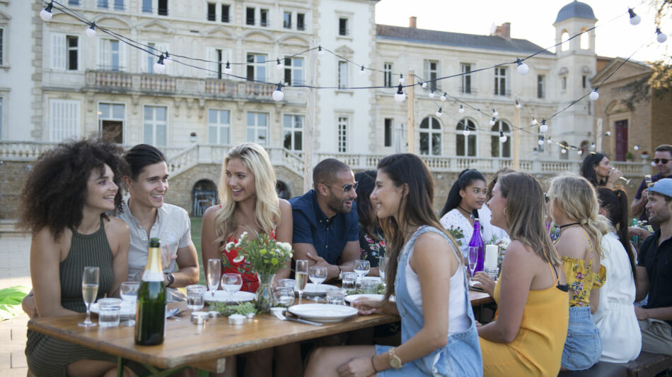 A group of people sitting around a table in front of a castle.