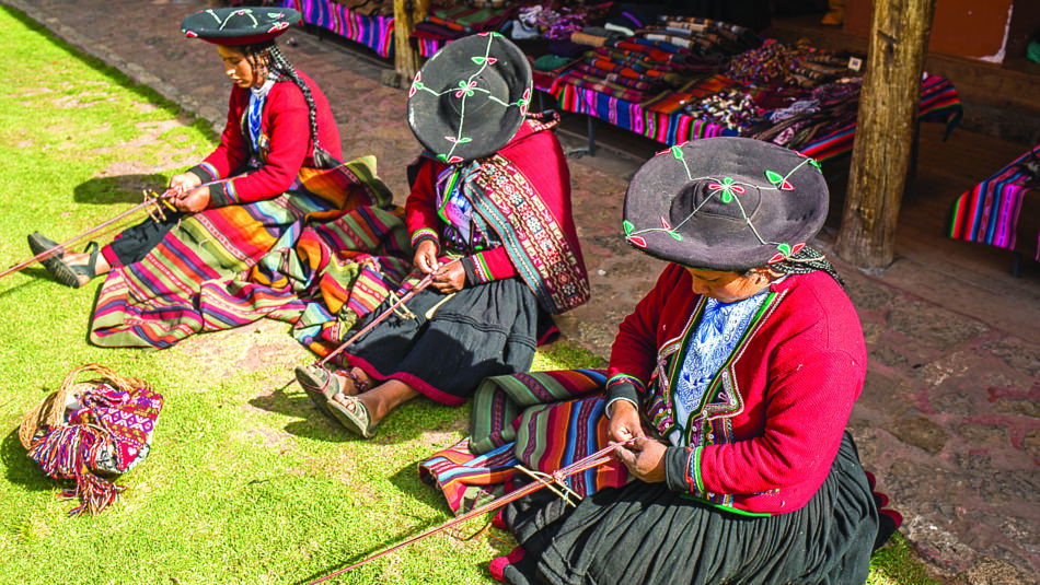 Colourfully dressed women weaving garments