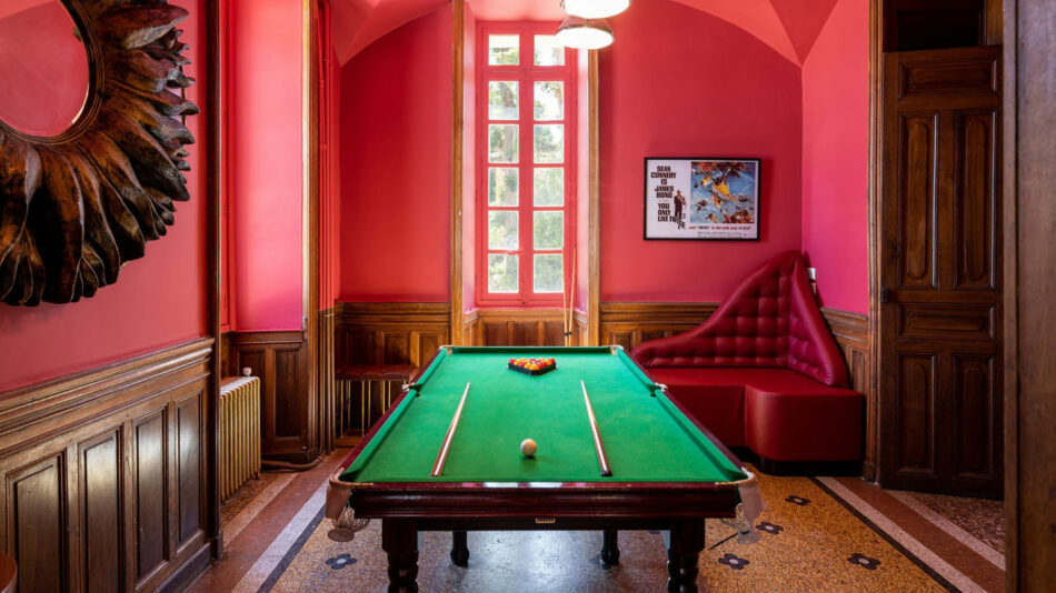 A pool table in a room with red walls.