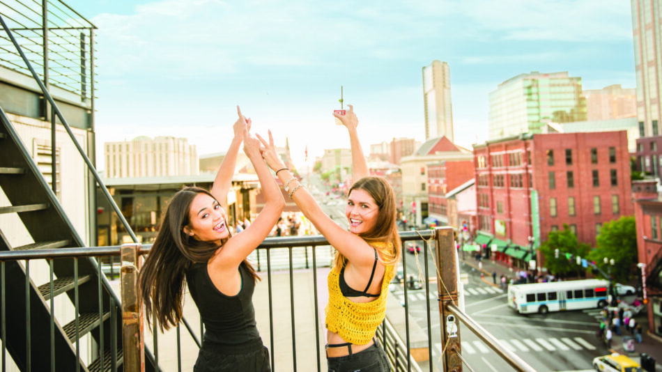 Two women standing on a balcony in one of the best cities to live in if you're single.