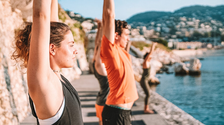 A group of people doing yoga in front of the water.