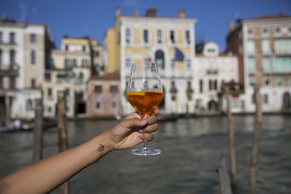 A person enjoying a glass of wine by the canal.