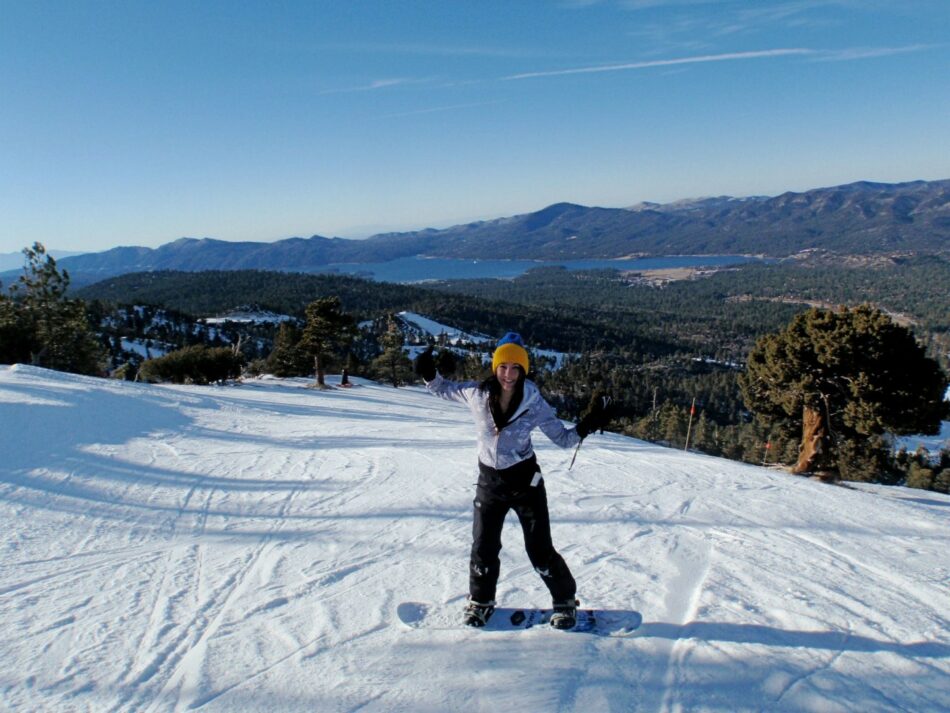 A woman enjoying a snowy slope on her snowboard.