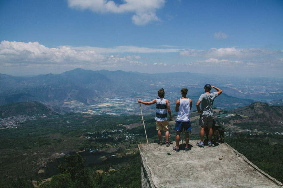 Three people standing on a ledge overlooking an affordable valley.