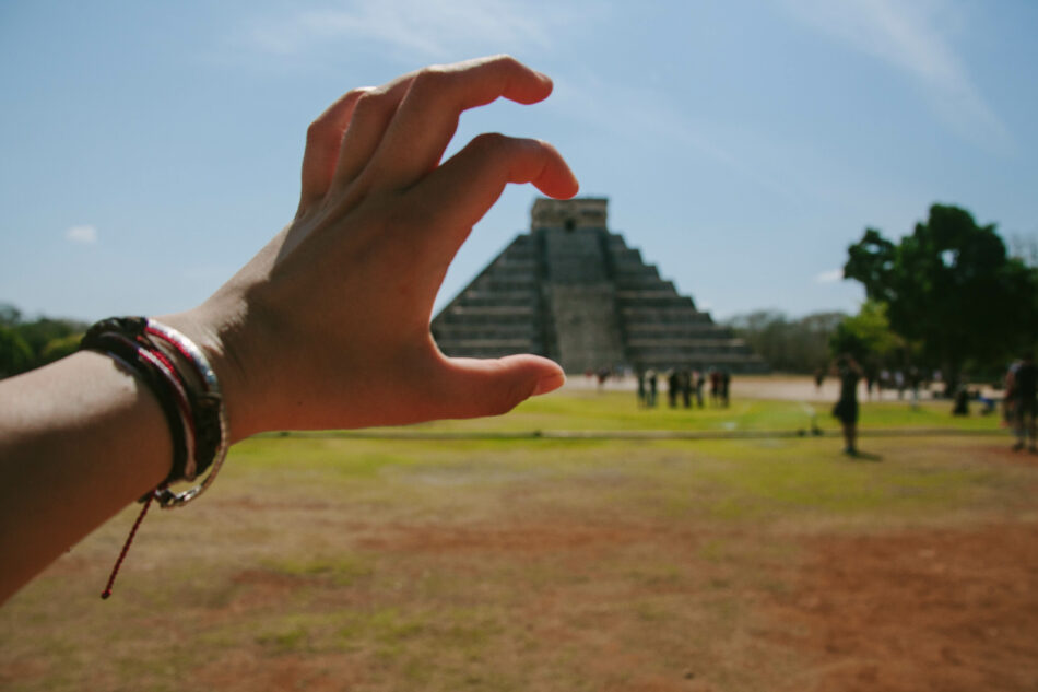 A person's hand in front of a pyramid in Chichen Itza, Mexico - pronunciation guide for Chichen Itza.