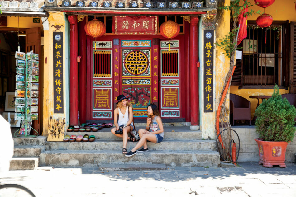 Two women sitting on the steps of a building in an affordable country.