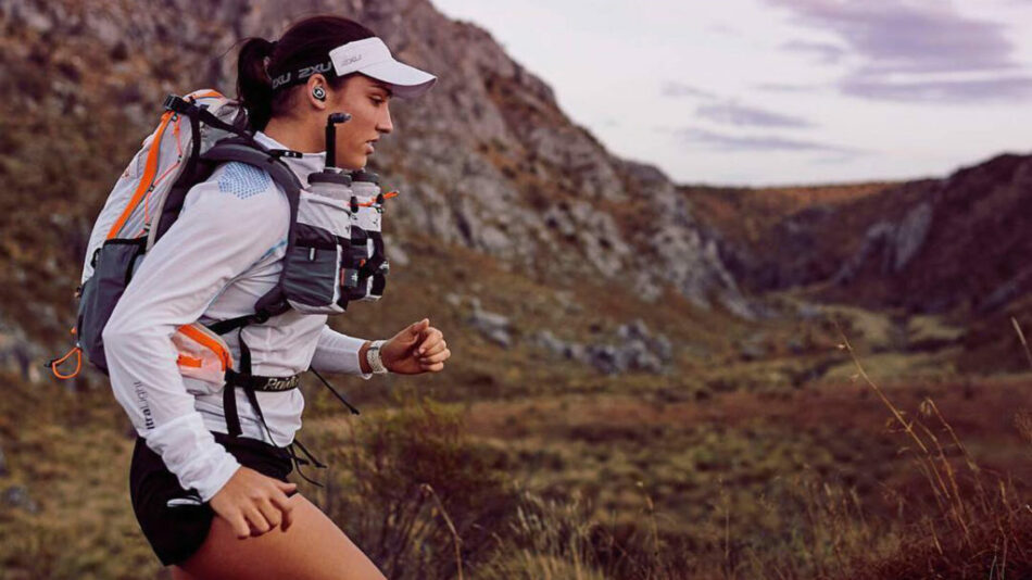 A woman participating in the 4 deserts race jogging in the mountains with a backpack.