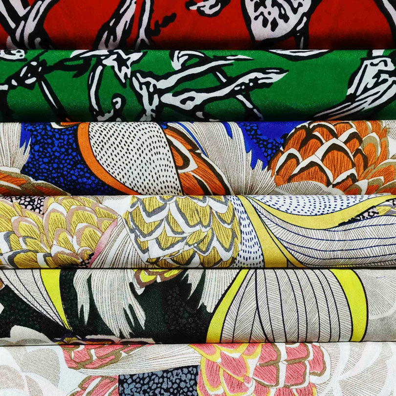 A stack of colorful fabric with a variety of designs, inspired by Hoi An fashion.