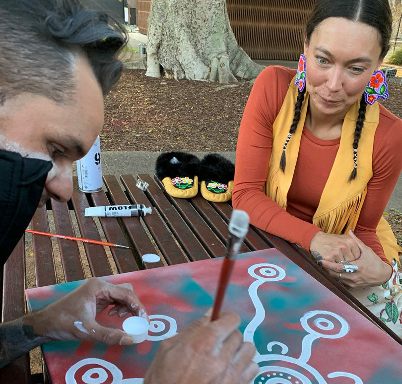 A man and a woman painting a picture on a table, featuring Sarain Fox.