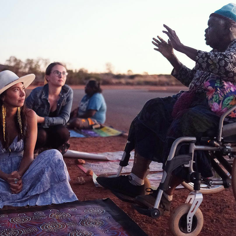 A wheelchair-bound woman, Sarain Fox, engages with a group of people.