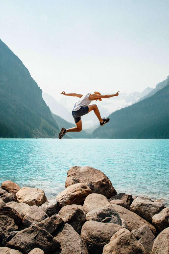 A man jumping in the air over a lake during group travel in Canada.