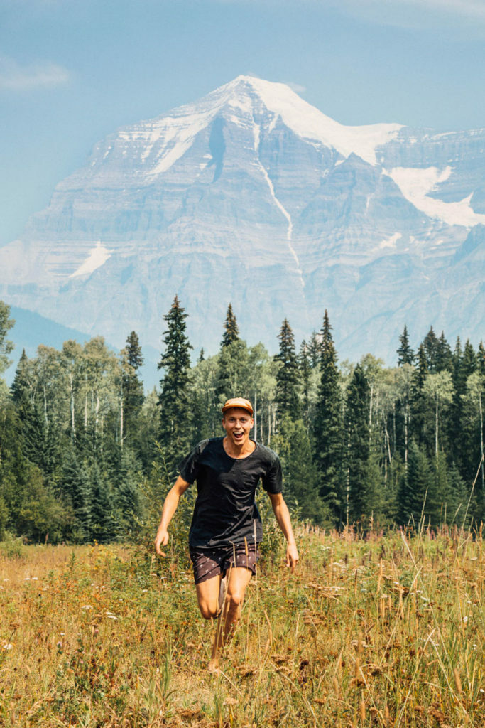 A man is running through a field while throwing a frisbee.