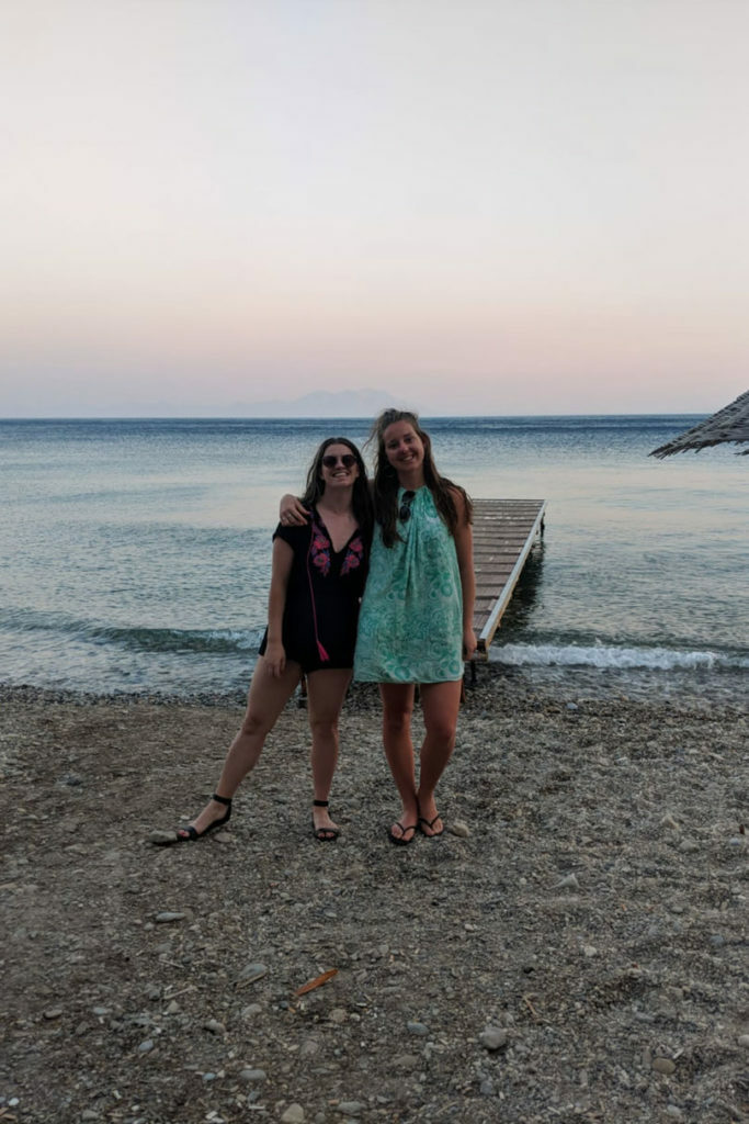 Two women practicing zero waste travel on the beach at sunset.