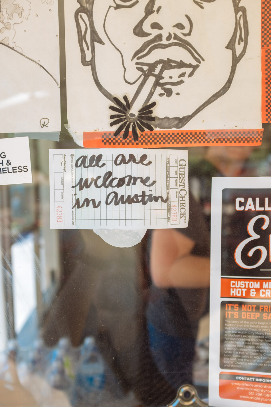 A man is smoking a cigarette in an Austin store window.