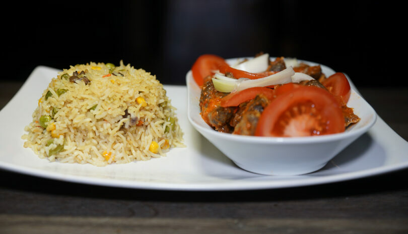 In an African travel guide, discover a beautiful plate of rice and vegetables displayed on a traditional table.