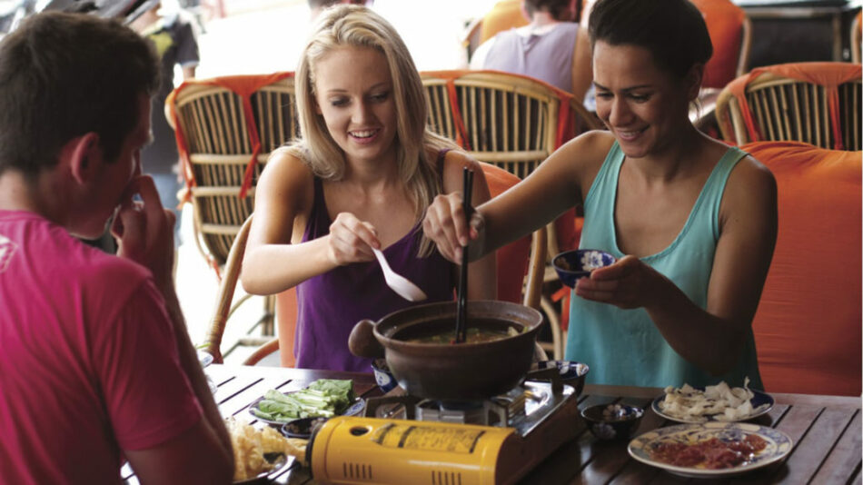 A group of people visit Cambodia to experience a table filled with delicious food.