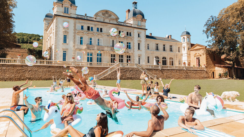 A group of people enjoying their gap year trips in a pool in front of a castle.