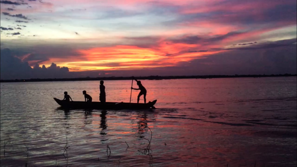 A group of people in a Cambodian boat at sunset.