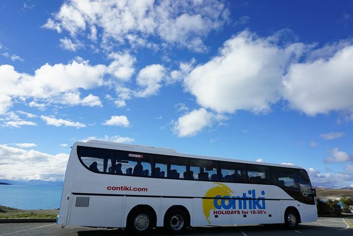 A white backpackers' bus parked in a parking lot.