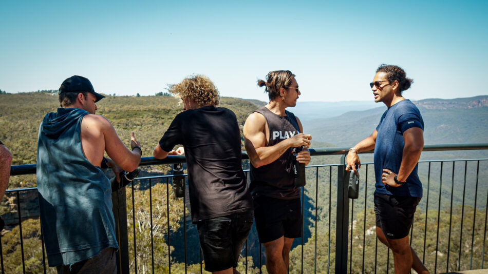 A group of men standing on a railing overlooking a mountain.