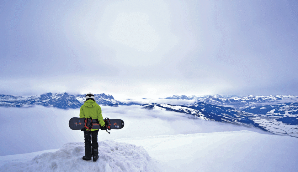 A person snowboarding on top of a mountain in Hopfgarten.