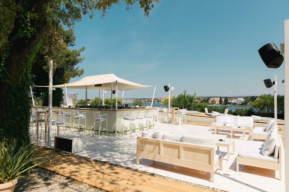 A large outdoor area with white furniture and umbrellas, perfect for relaxing during Croatia festivals.