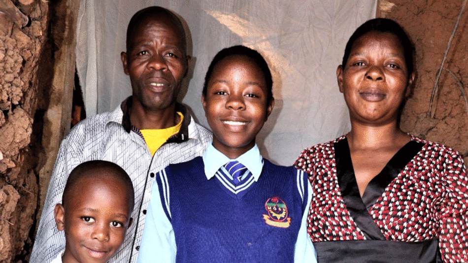 A family is posing for a picture in front of a dirt wall, reflecting a mirror of hope.