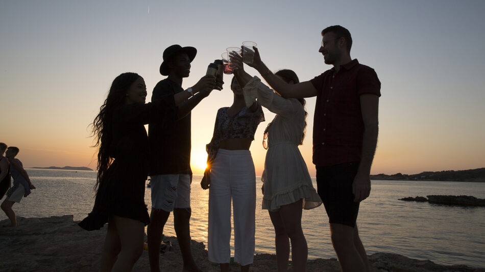 A group of people traveling together toasting at sunset in 2019.