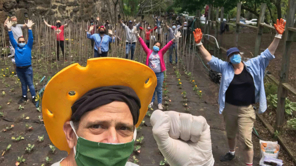 A group of people wearing masks and gloves in a garden, engaging in US food experiences.