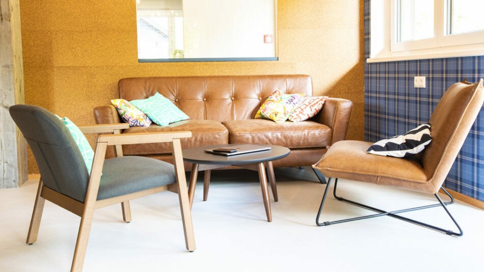 A living room with a brown leather couch and a coffee table at Gasthof Schoneck.