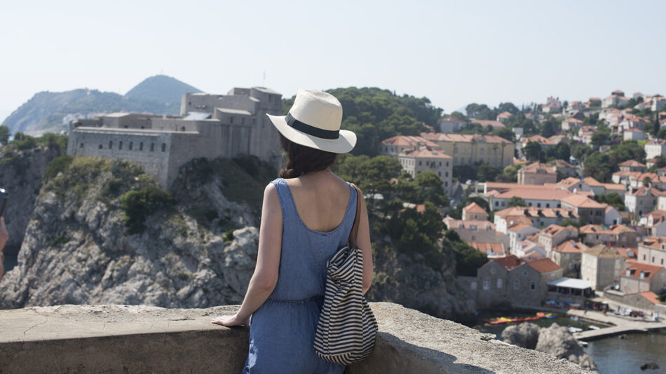 A woman in a hat is enjoying some self-care while looking out over the city of Dubrovnik.